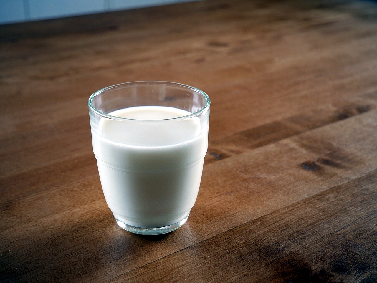 Vaso de leche sobre una mesa de madera