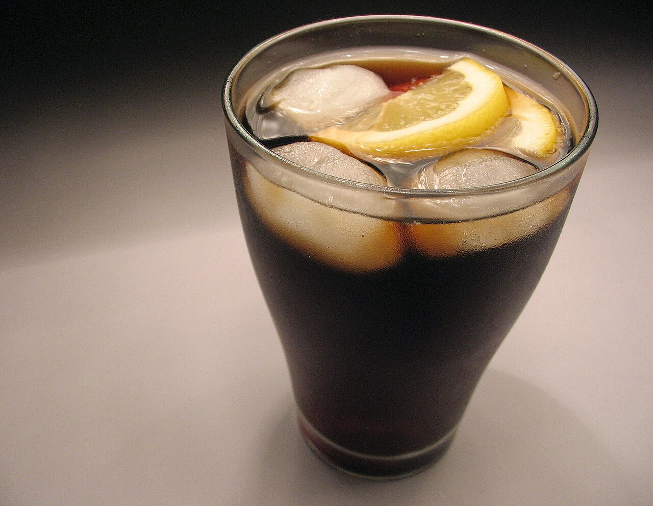 Vaso de refresco de cola con hielo y limón
